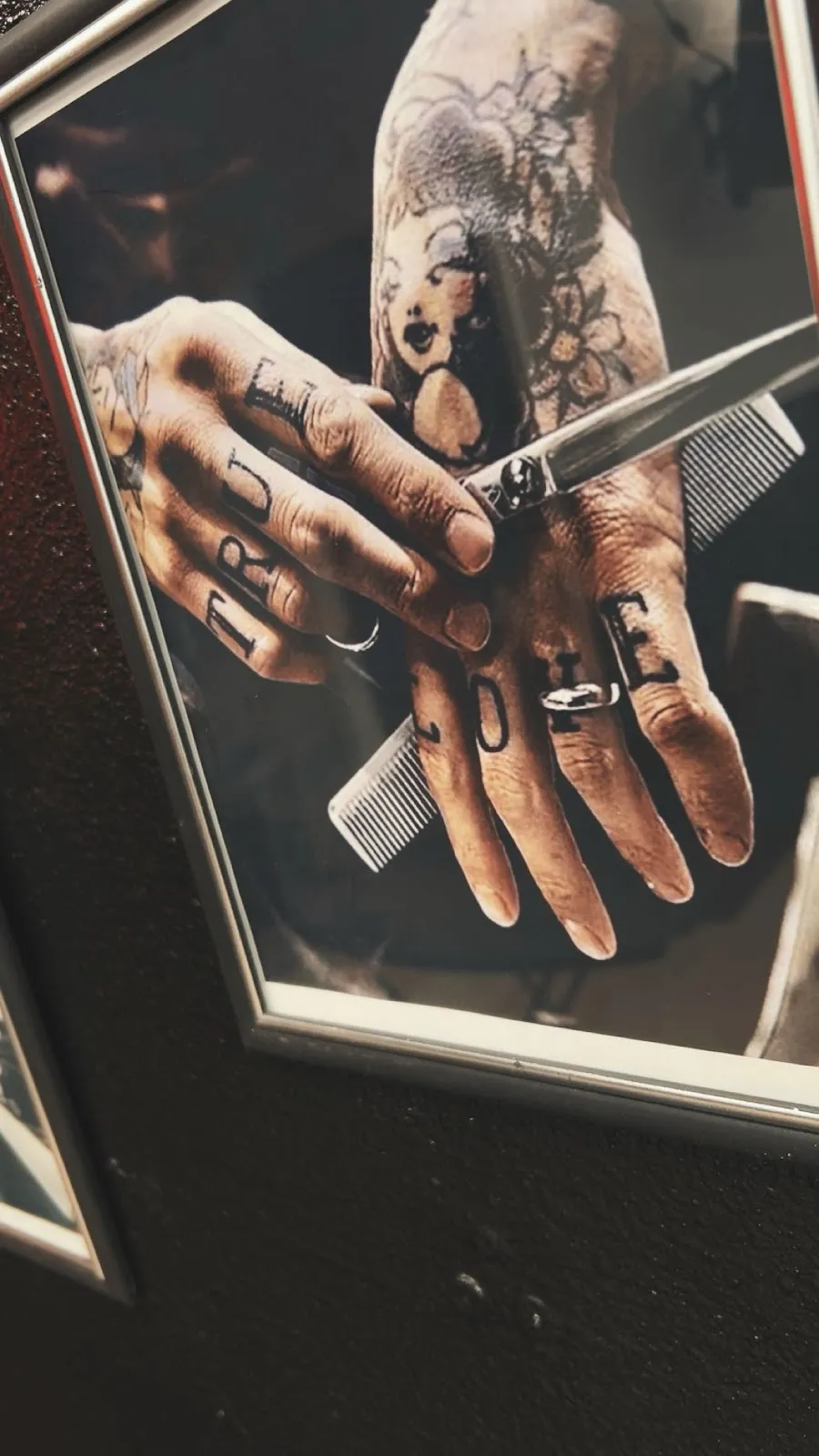 A framed True Love straight-razor print on the shop's dark wall